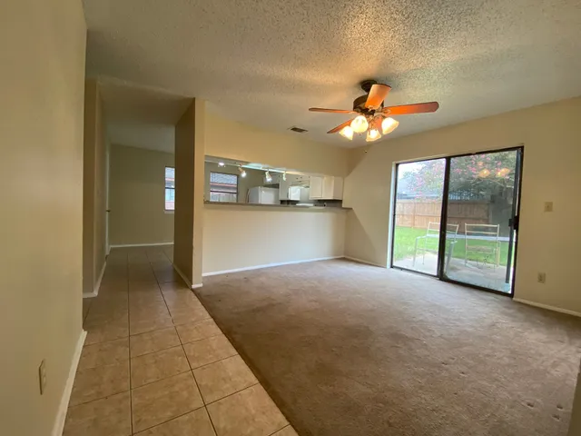 an empty room with a chandelier fan and windows