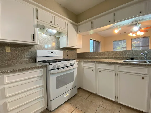 a view of a kitchen with kitchen island granite countertop white cabinets and a sink