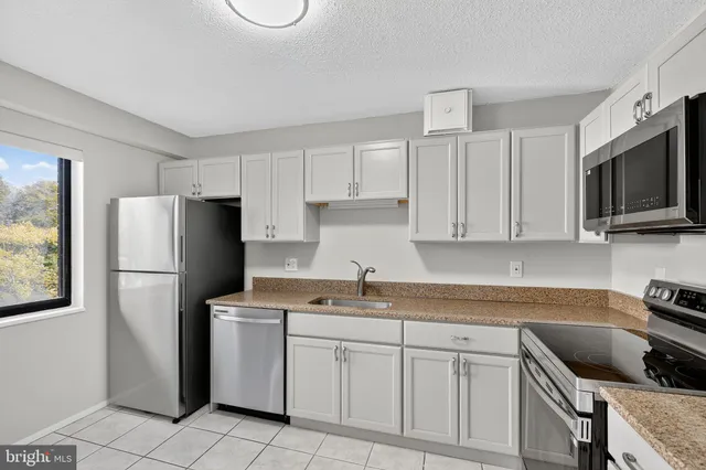 a kitchen with white cabinets stainless steel appliances and a window