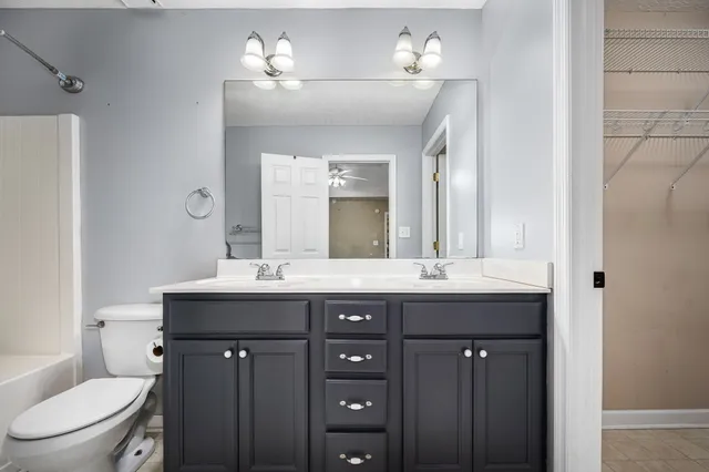a spacious bathroom with a double vanity sink toilet mirror and bathtub