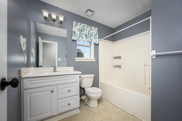 an empty room with windows and chandelier fan