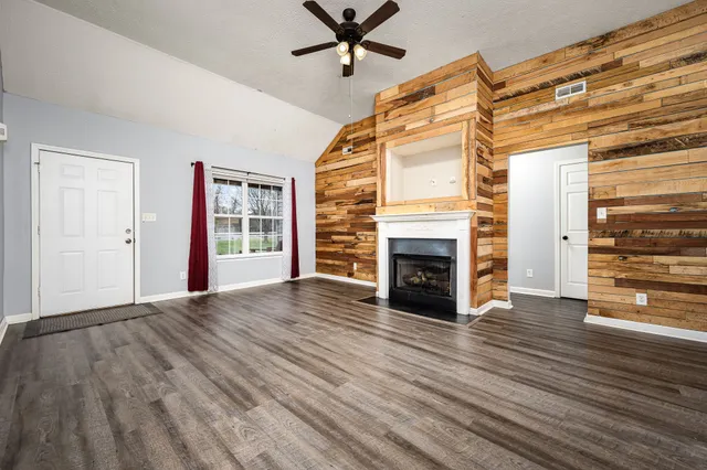 a view of a livingroom with wooden floor a fireplace and window