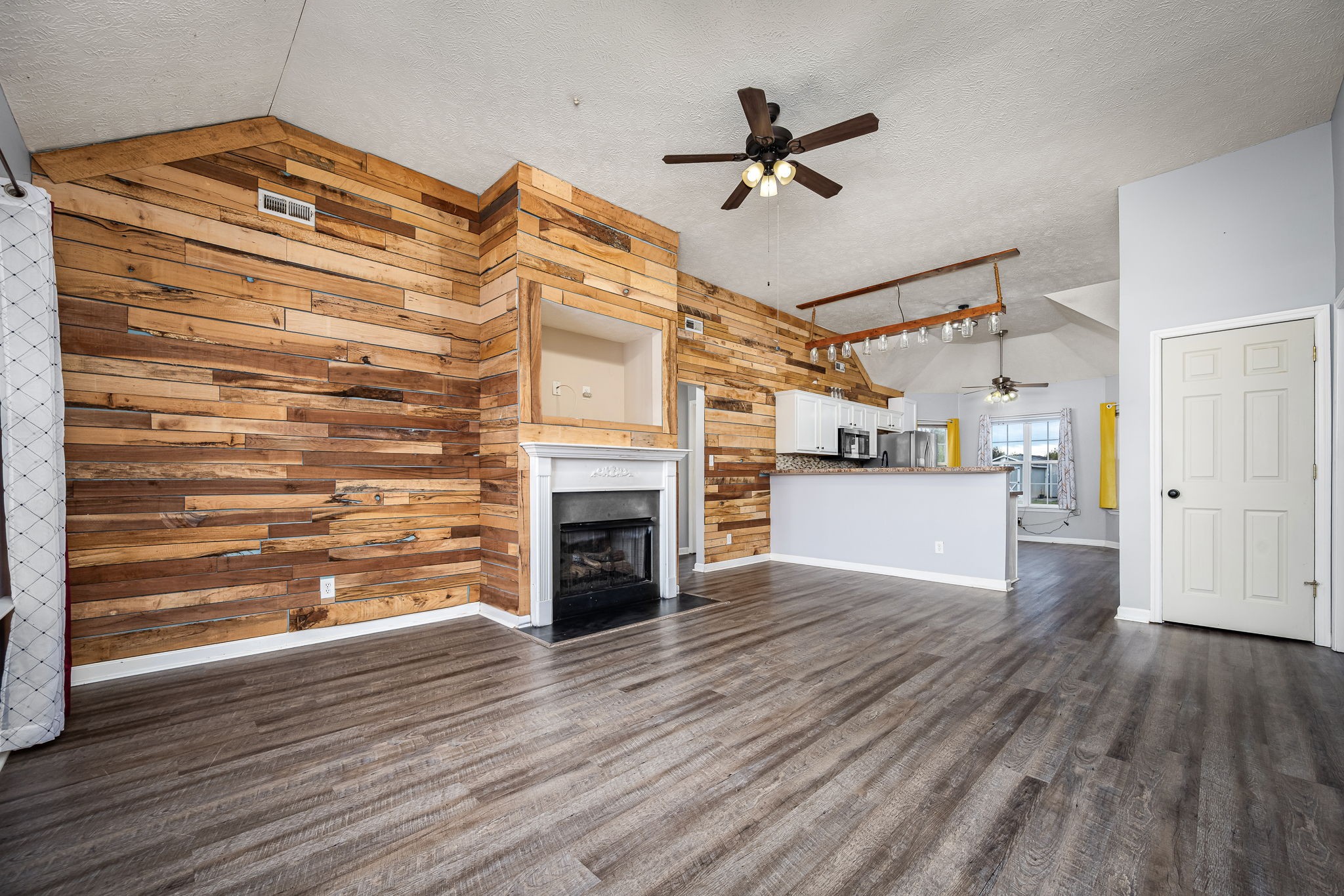 8100 Cedar Forest Road Lascassas, TN 37085 - Photo 8 of 52 a view of a livingroom with a fireplace a ceiling fan and wooden floor