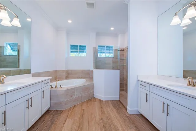 a spacious bathroom with a double vanity sink a mirror and a bathtub