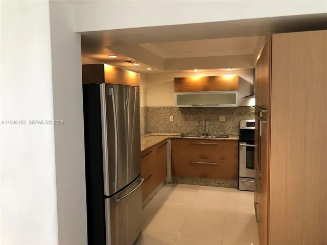 a view of a refrigerator in kitchen and an empty room