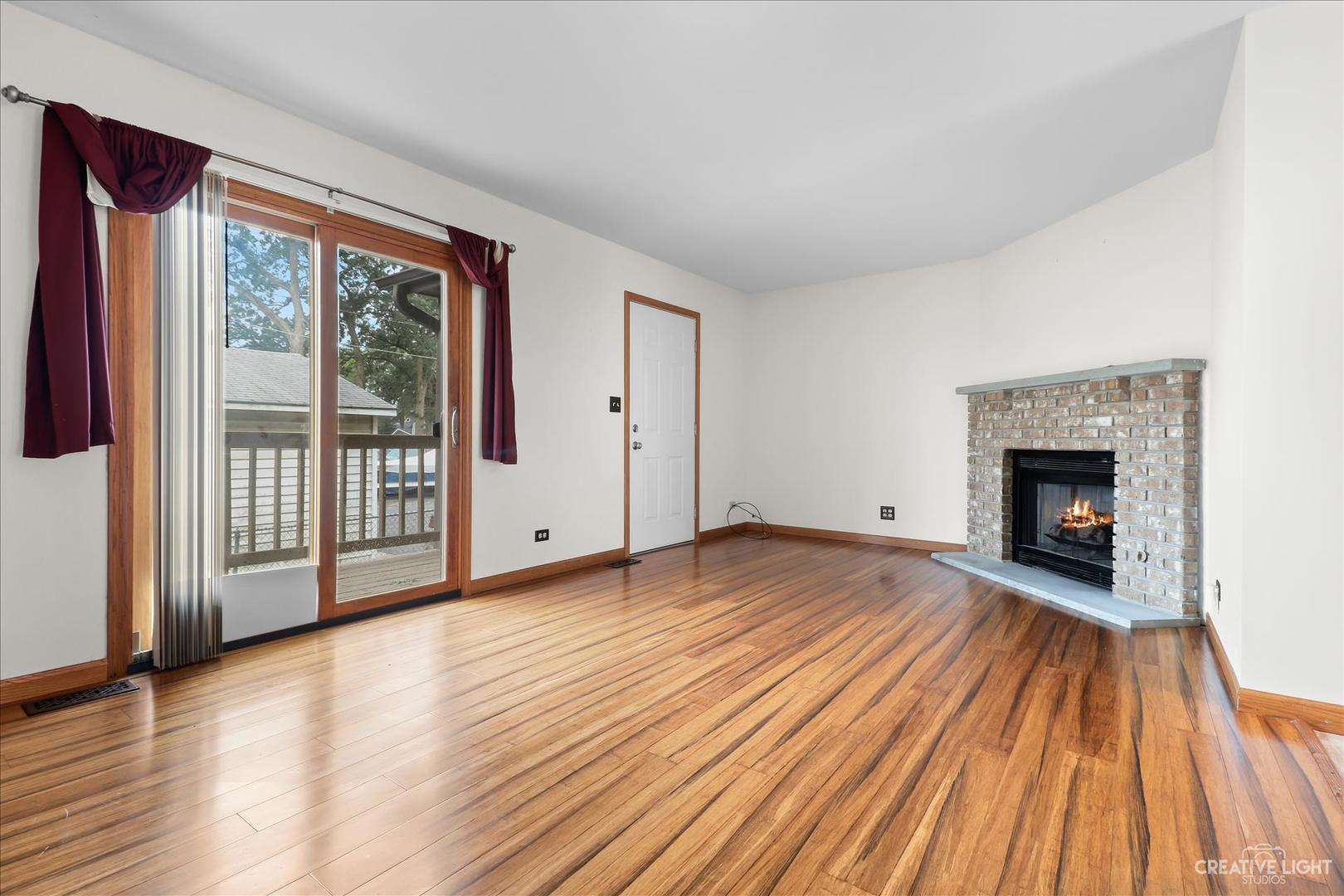 150 Eagle Point Road, Unit J Fox Lake, IL 60020 - Photo 4 of 16 a view of empty room with wooden floor and fireplace