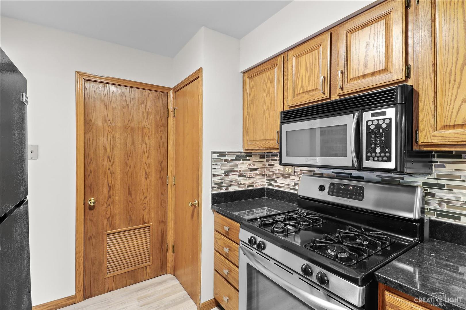 150 Eagle Point Road, Unit J Fox Lake, IL 60020 - Photo 7 of 16 a kitchen with granite countertop a stove and a microwave