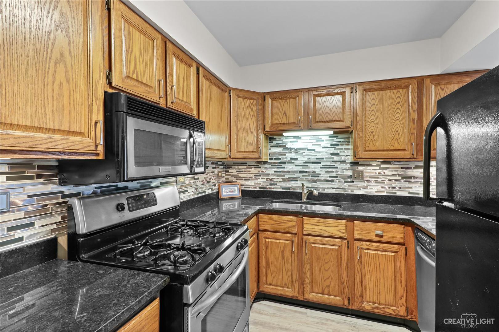 150 Eagle Point Road, Unit J Fox Lake, IL 60020 - Photo 8 of 16 a kitchen with granite countertop a stove and a microwave