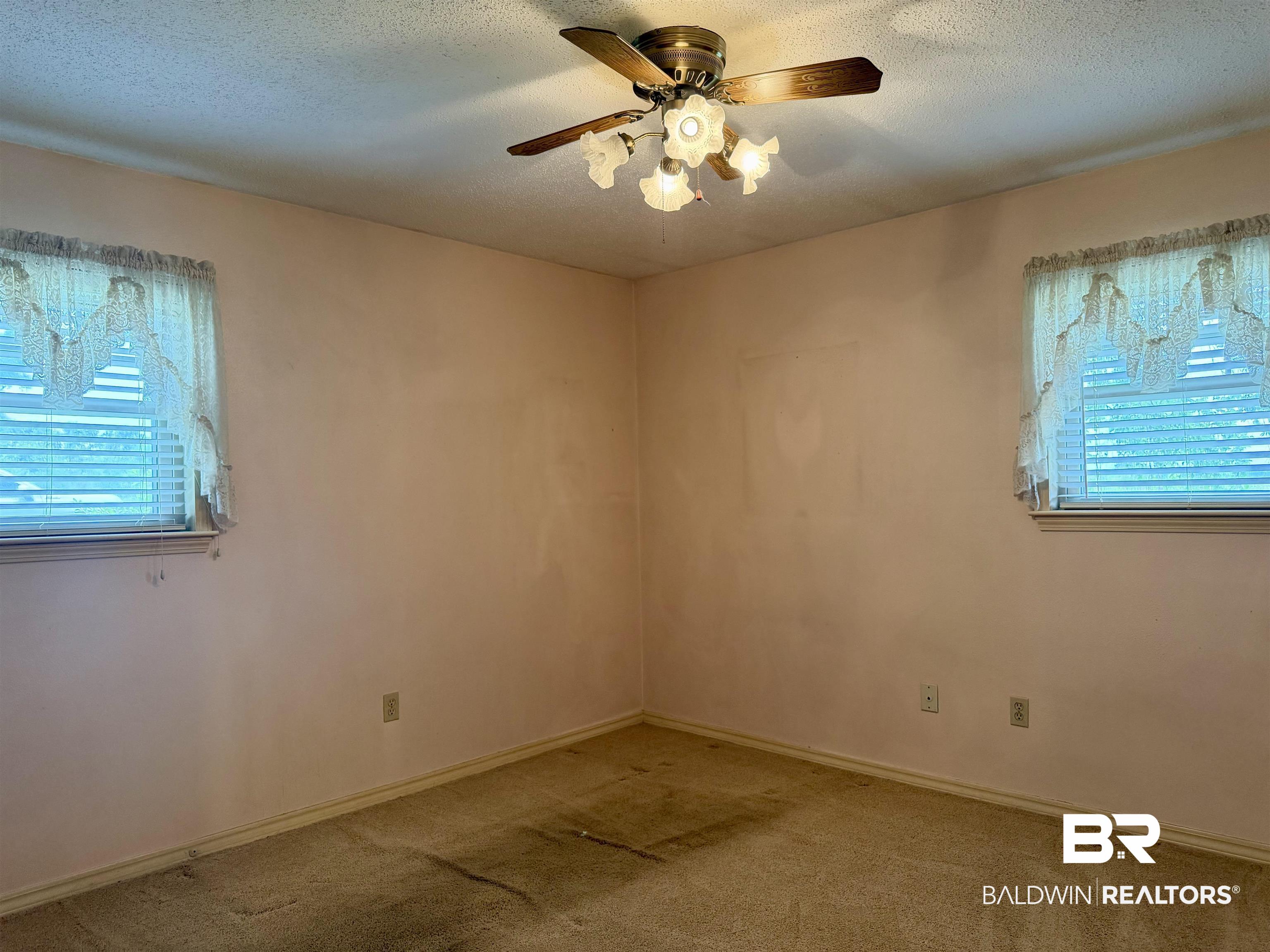 3642 Old Castleberry Road Brewton, AL 36426 - Photo 9 of 14 Carpeted interior room featuring two windows with horizontal blinds, a ceiling fan with integrated lighting, and painted walls