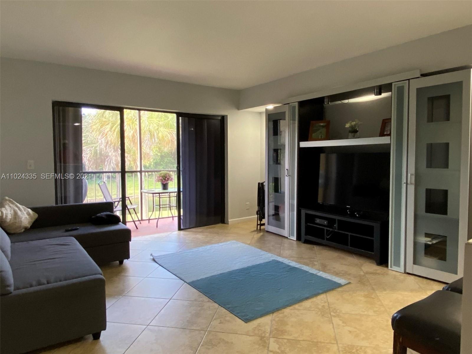 209 Lakeview Drive, Unit 202 Weston, FL 33326 - Photo 9 of 25 a living room with furniture and a flat screen tv