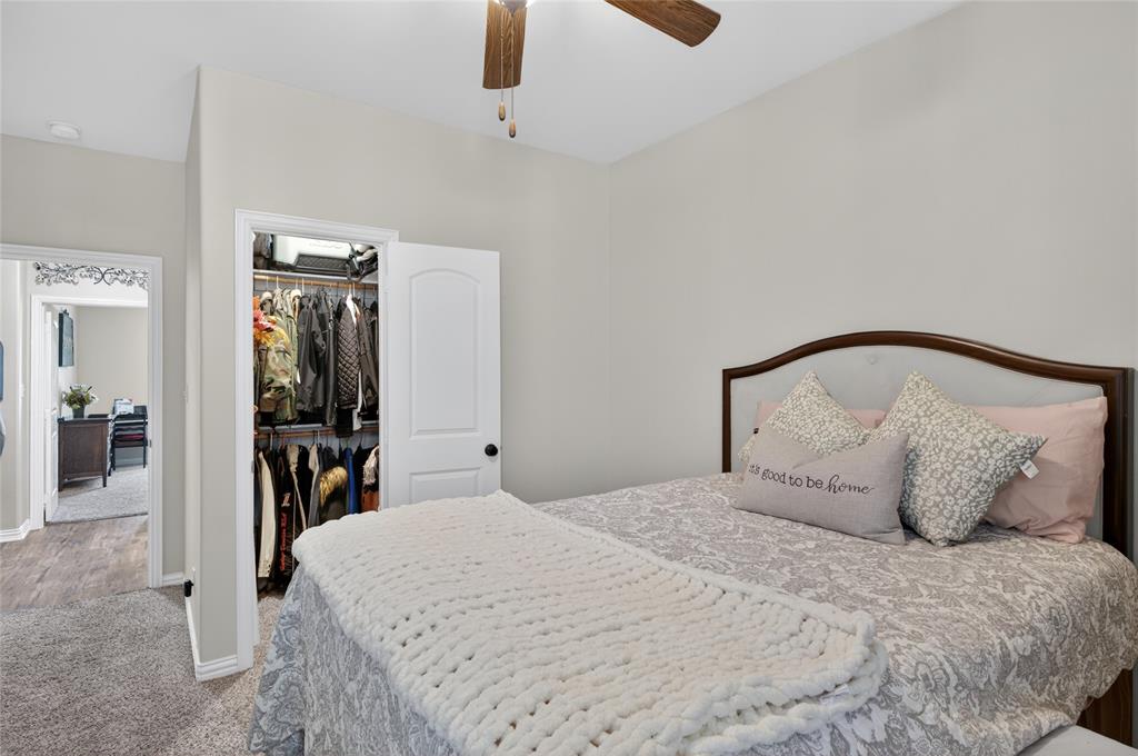 701 West Lamberth Road Sherman, TX 75092 - Photo 25 of 37 Bedroom featuring light gray wall paint, a walk-in closet with built-in shelving and hanging rods, a wood-finish ceiling fan, and carpeted flooring