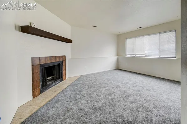 a view of an empty room with a fireplace and a window