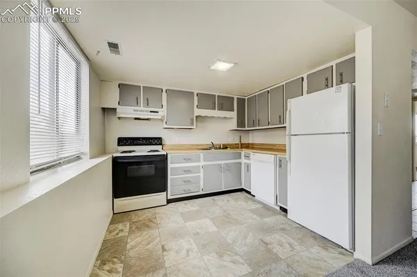 a kitchen with a refrigerator a stove top oven and cabinets