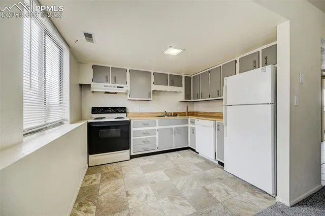 a kitchen with a refrigerator a stove top oven and cabinets