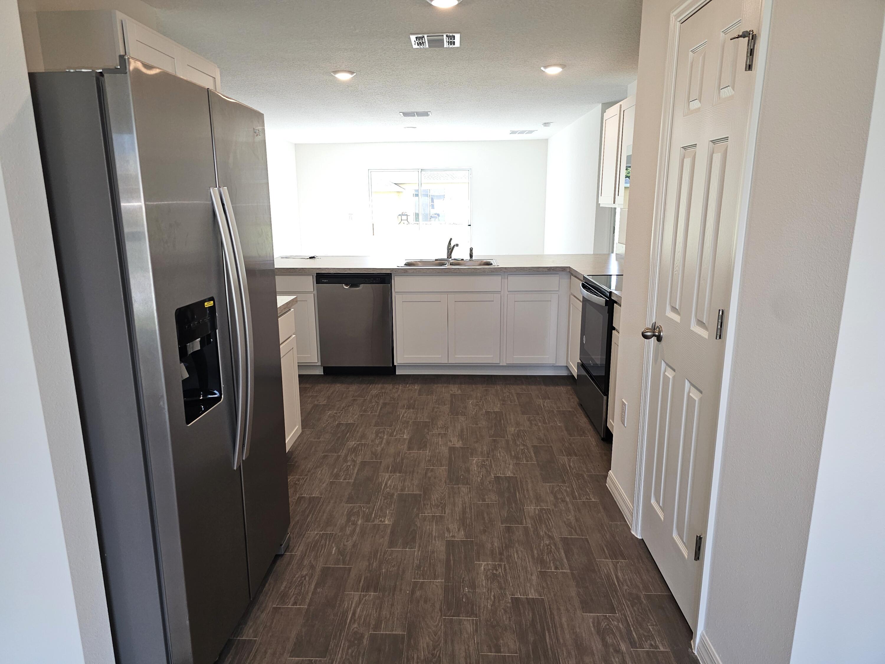 3681 Southwest Haines Street Port St. Lucie, FL 34953 - Photo 3 of 19 a kitchen with stainless steel appliances a refrigerator a sink a stove a microwave and cabinets