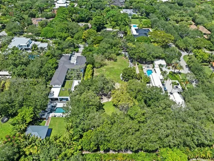 an aerial view of residential house with outdoor space and trees all around