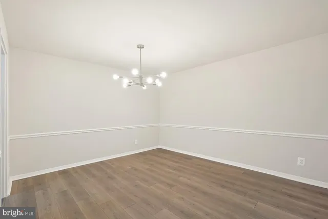 a view of an empty room with wooden floor and fan