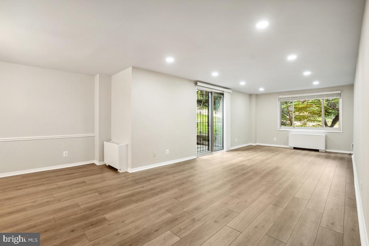 1900 Lyttonsville Road, Unit 216 Silver Spring, MD 20910 - Photo 7 of 38 a view of an empty room with wooden floor and a window