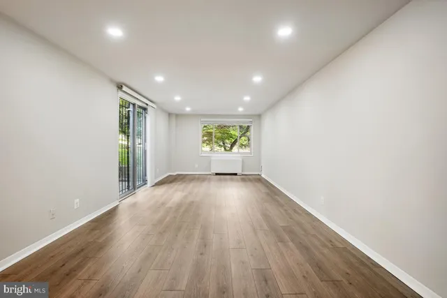 an empty room with wooden floor and windows
