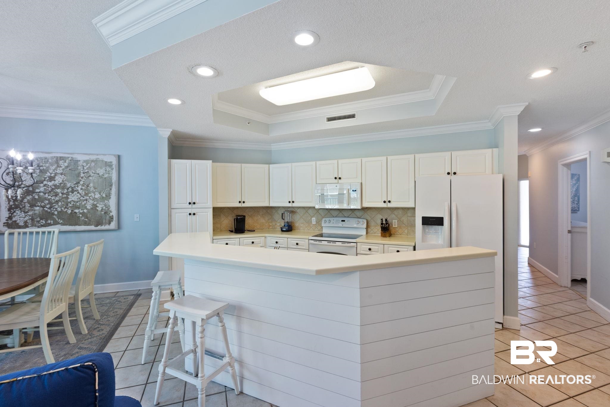 27580 Canal Road, Unit 1112 Orange Beach, AL 36561 - Photo 9 of 50 Kitchen featuring a tray ceiling, light countertops, ornamental molding, tasteful backsplash, and white appliances
