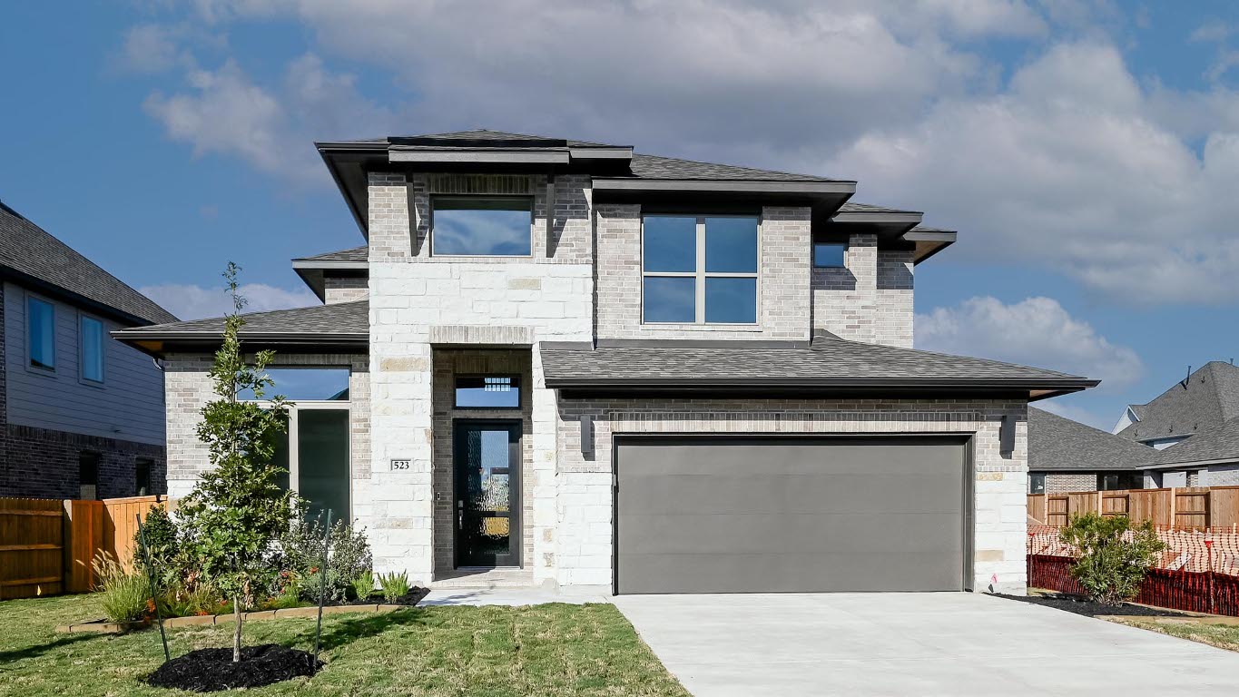 View of front of property featuring roof with shingles, stone siding, an attached garage, concrete driveway, and brick siding