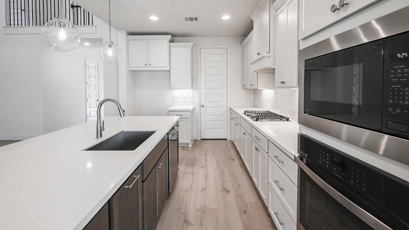 523 Prickly Poppy Loop Kyle, TX 78640 - Photo 16 of 40 Kitchen featuring appliances with stainless steel finishes, decorative light fixtures, white cabinetry, light wood-type flooring, and decorative backsplash