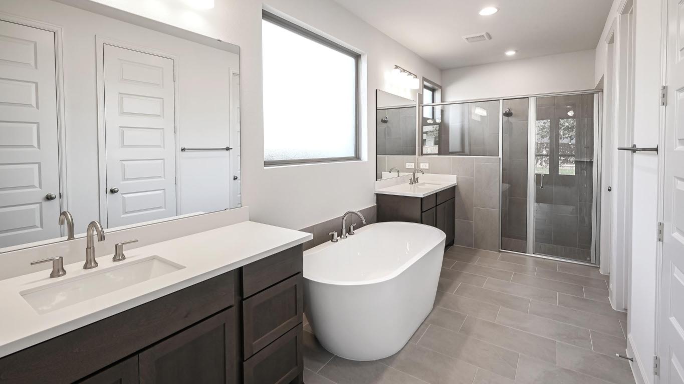 523 Prickly Poppy Loop Kyle, TX 78640 - Photo 20 of 40 Bathroom featuring a stall shower, a freestanding tub, two vanities, and light tile patterned floors