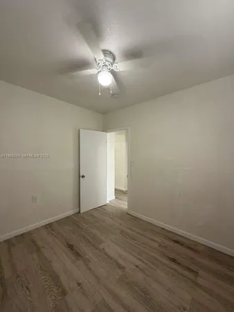 an empty room with wooden floor and fan