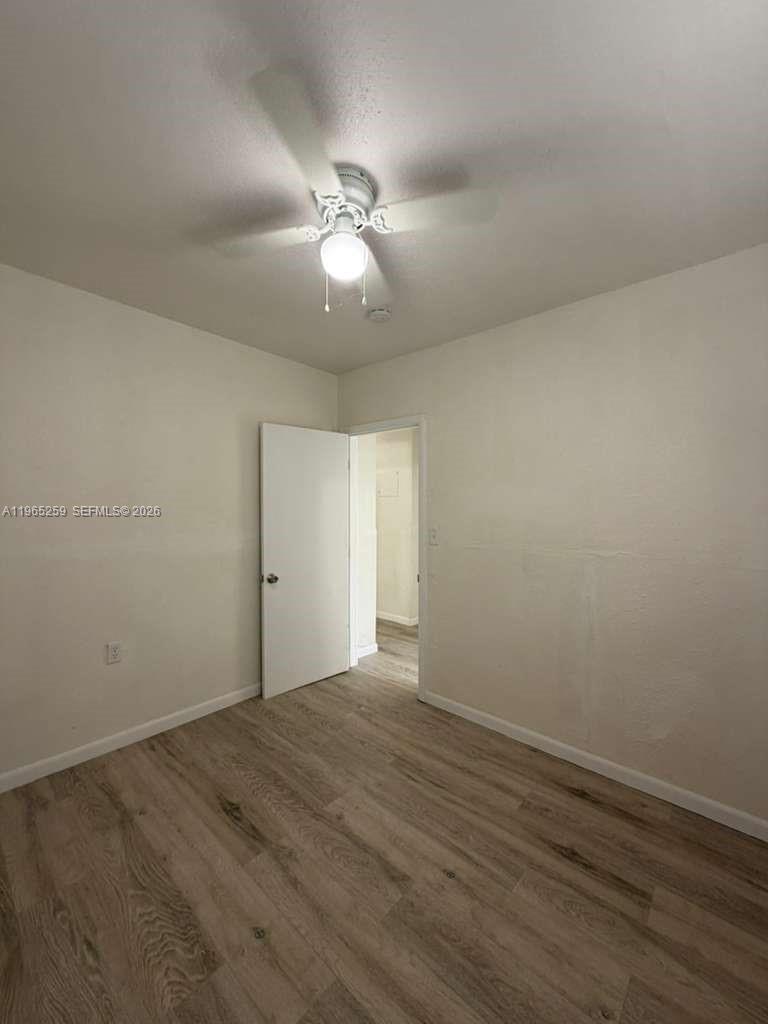 140 Northwest 13th Street, Unit 154 Miami, FL 33136 - Photo 12 of 18 an empty room with wooden floor and fan
