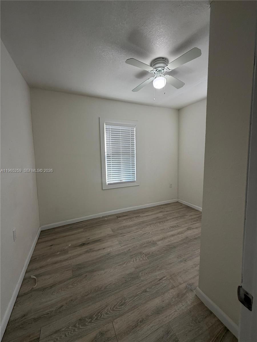 140 Northwest 13th Street, Unit 154 Miami, FL 33136 - Photo 16 of 18 an empty room with wooden floor fan and windows