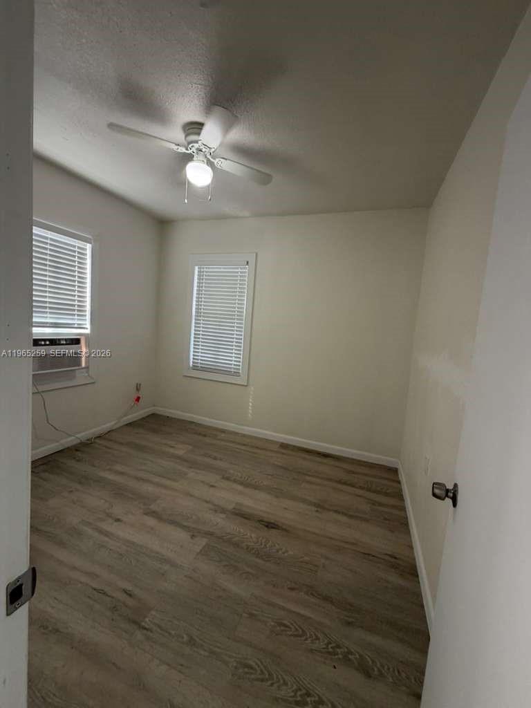 140 Northwest 13th Street, Unit 154 Miami, FL 33136 - Photo 18 of 18 an empty room with wooden floor fan and windows