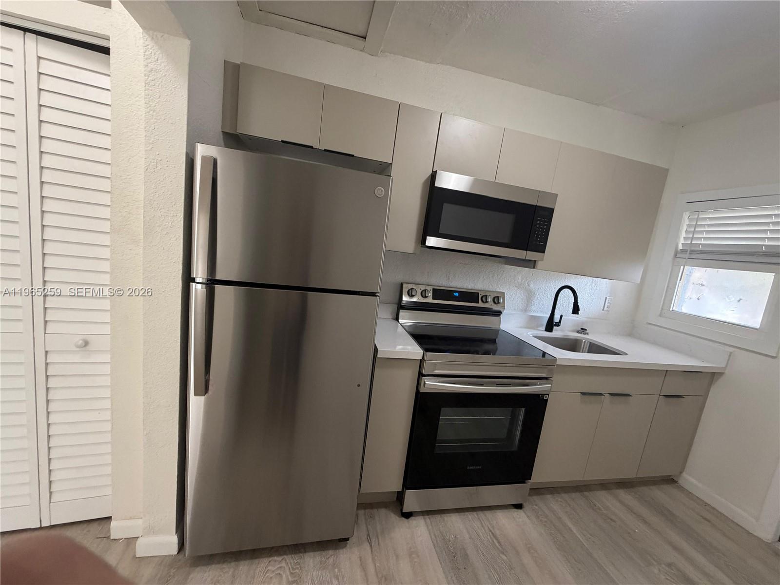140 Northwest 13th Street, Unit 154 Miami, FL 33136 - Photo 6 of 18 a kitchen with stainless steel appliances a refrigerator sink and microwave
