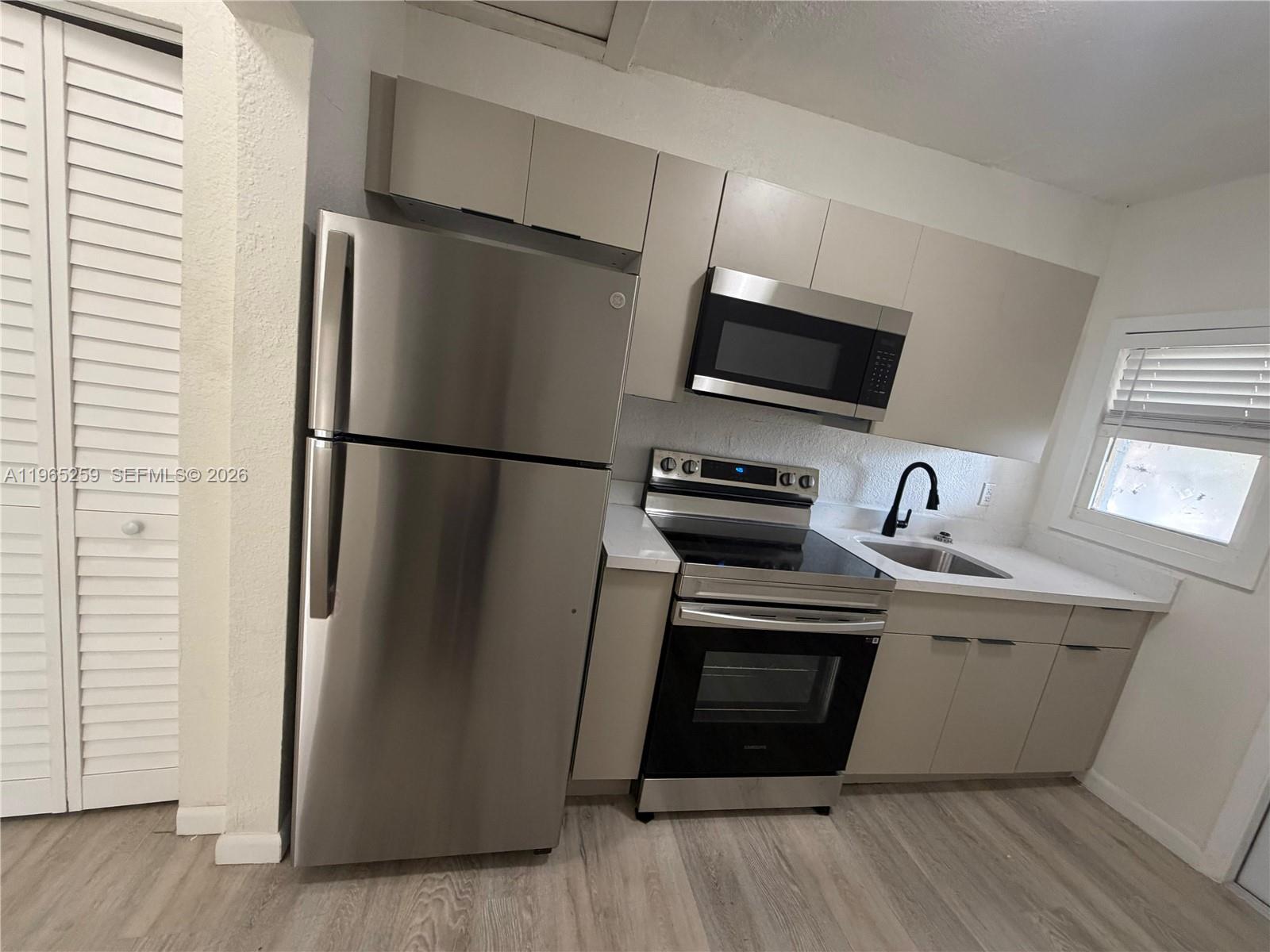 140 Northwest 13th Street, Unit 154 Miami, FL 33136 - Photo 7 of 18 a kitchen with stainless steel appliances a refrigerator sink and microwave