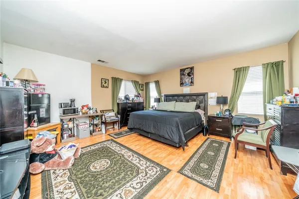 a bedroom with a bed a table and chair with wooden floor