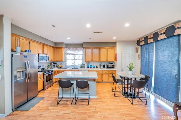 a kitchen with stainless steel appliances granite countertop table chairs and a refrigerator