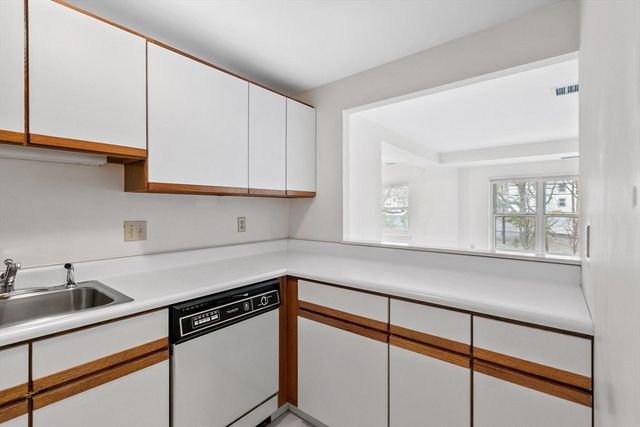 a kitchen with stainless steel appliances granite countertop a sink a stove and white cabinets with wooden floor