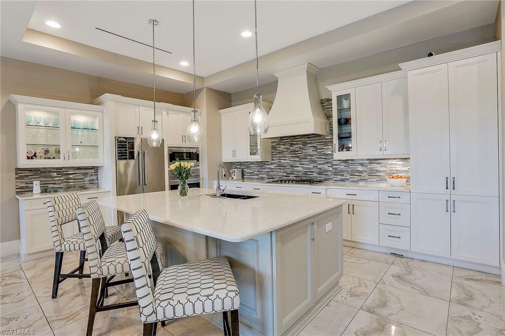 16776 Brightling Way Naples, FL 34110 - Photo 11 of 35 a kitchen with stainless steel appliances kitchen island granite countertop a table chairs sink and cabinets