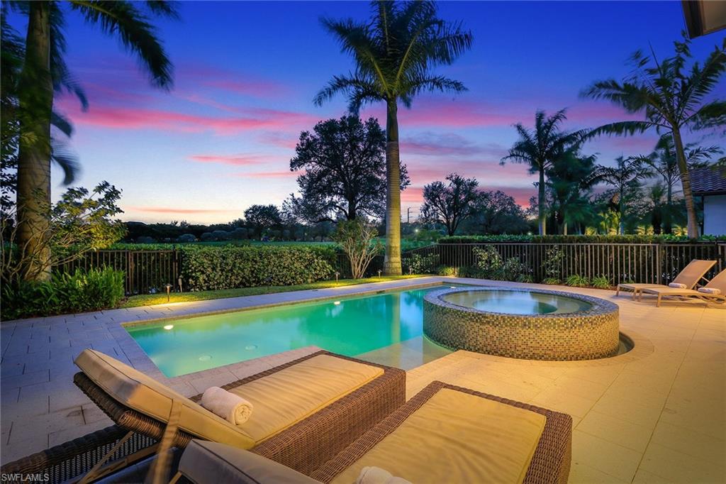 16776 Brightling Way Naples, FL 34110 - Photo 2 of 35 a view of a swimming pool with a table and chairs under an umbrella