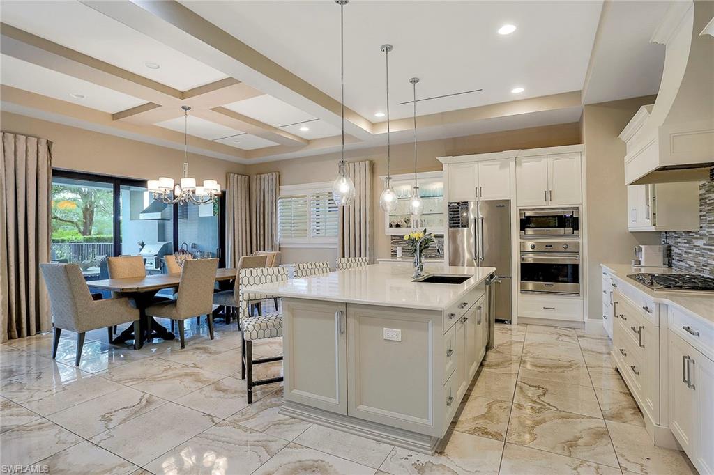 16776 Brightling Way Naples, FL 34110 - Photo 10 of 35 a kitchen with stainless steel appliances kitchen island granite countertop a table chairs sink and cabinets