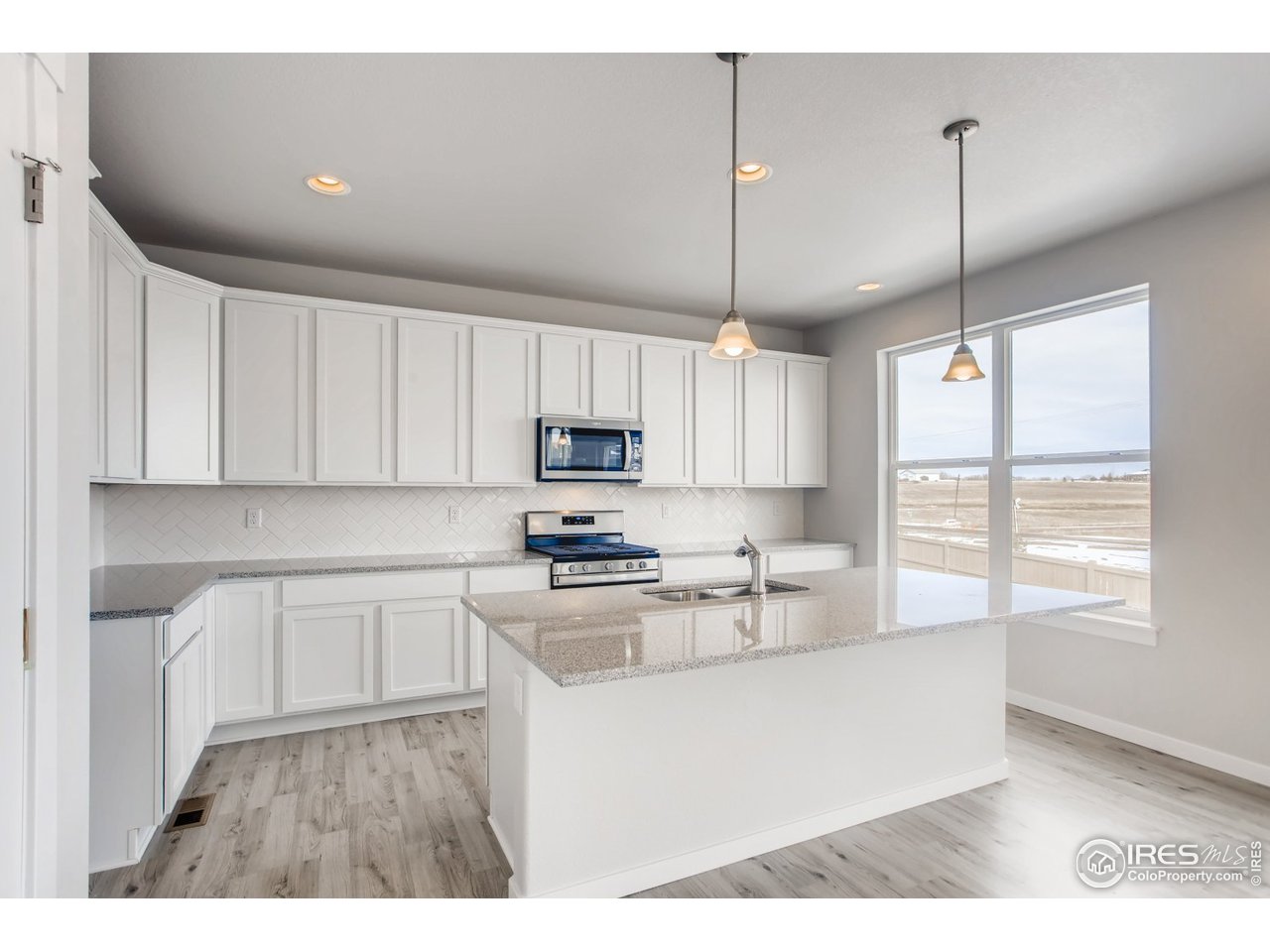 796 Lowry Lane Berthoud, CO 80513 - Photo 13 of 28 a kitchen with stainless steel appliances white cabinets a sink a window and wooden floor