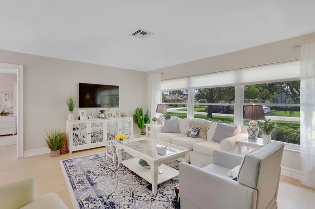 a living room with furniture a flat screen tv and a floor to ceiling window