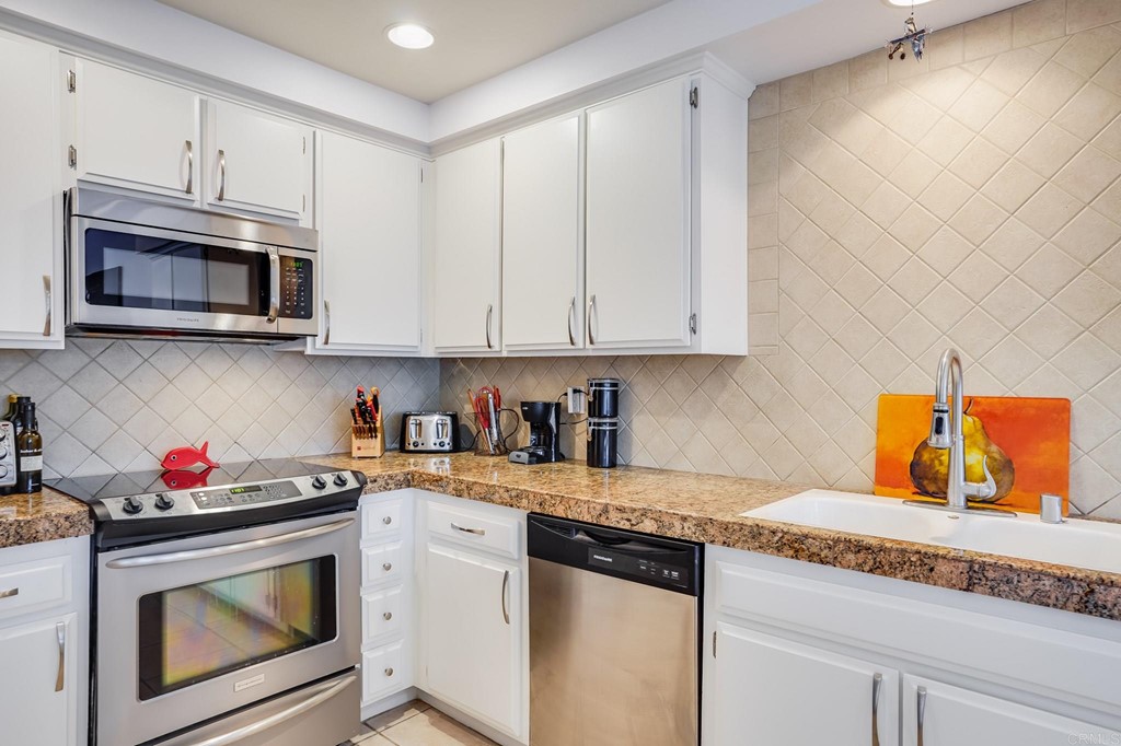 573 South Sierra Avenue, Unit 8 Solana Beach, CA 92075 - Photo 12 of 54 a kitchen with granite countertop white cabinets stainless steel appliances and a sink