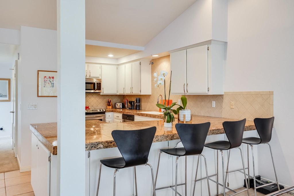 573 South Sierra Avenue, Unit 8 Solana Beach, CA 92075 - Photo 16 of 54 a kitchen with a dining table chairs and cabinets