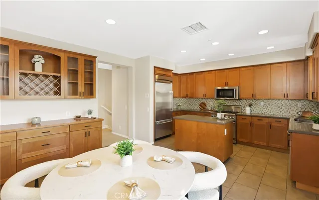 a kitchen with stainless steel appliances granite countertop a kitchen island a stove a sink a dining table and chairs