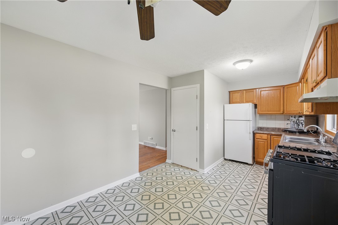 7835 Elyria Road Medina, OH 44256 - Photo 26 of 46 Kitchen with freestanding refrigerator, range with gas cooktop, under cabinet range hood, a sink, and a ceiling fan