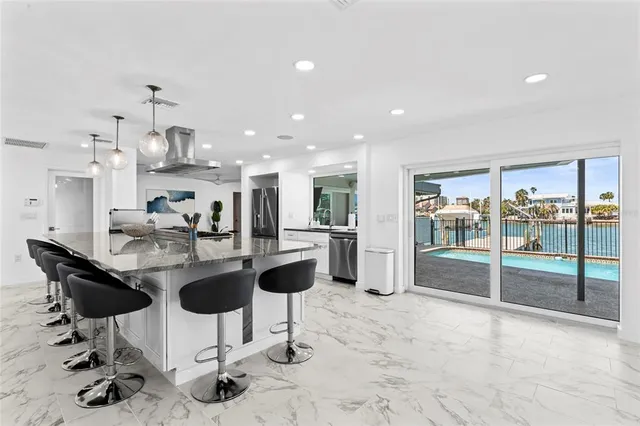 a kitchen with stainless steel appliances kitchen island granite countertop a refrigerator and chairs