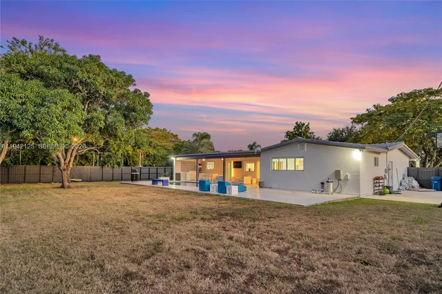 a view of a house with a yard and a large tree