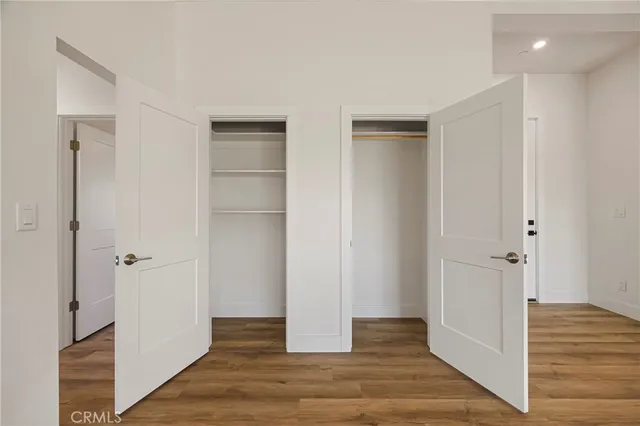 a view of an empty room with wooden floor and a hallway