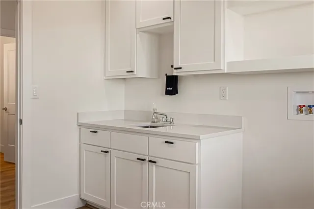 a kitchen with white cabinets and sink