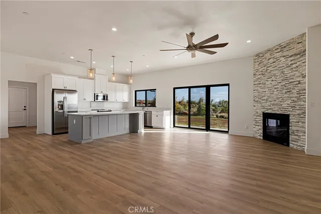 a large kitchen with stainless steel appliances granite countertop a stove top oven a refrigerator and a fireplace with wooden floor